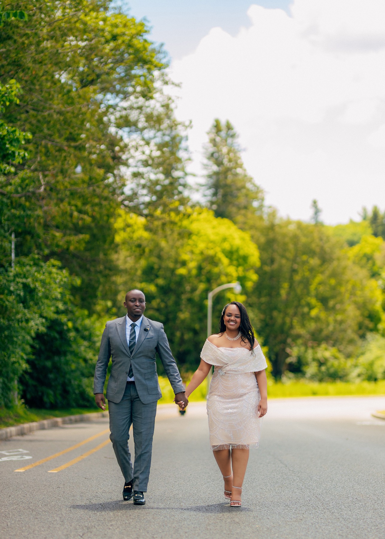 Hope and Arsene walking hand in hand down a tree-lined road